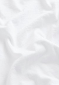 Mjukt vitt tyg med subtila veck och en jämn, slät yta, jämnt belyst med naturligt ljus.