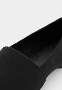 Pantofle negre cu o exterior din piele netedă, vârf rotund și o detaliu subtil de cusătură de-a lungul marginii superioare; design cu profil redus.