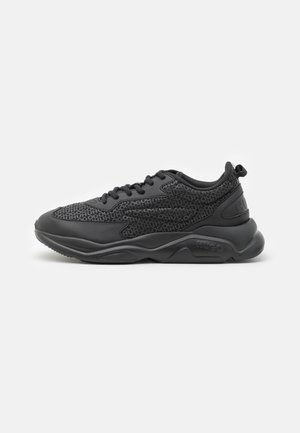 Black sneakers with a textured upper featuring repeated logo patterns, padded collar, and a thick rubber sole for cushioning.