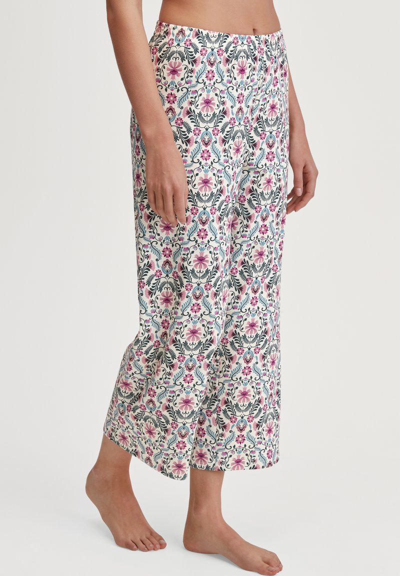 Lichte, bedrukte pyjamabroek met een bloemdessin in roze, groen en blauw op een witte achtergrond; ontspannen pasvorm, enkel lengte.