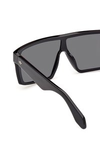 Ochelari de soare negri cu un design unghiular și lentile întunecate. Confecționați din plastic lucios, având un logo subtil aurit pe lateral.