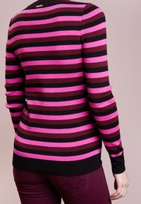 Maglione a righe con strisce orizzontali rosa, borgogna e nere. Realizzato in tessuto a maglia, presenta maniche lunghe e scollatura a girocollo.