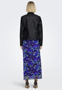 Giacca di pelle nera, vestito lungo con stampa floreale in toni di blu e verde, scarpe con tacco alto nere, mostrato da dietro su uno sfondo neutro.