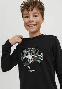Felpa nera con collo a girare, caratterizzata da una grafica colorata di un teschio su un skateboard. Il materiale sembra morbido, adatto per un abbigliamento casual.