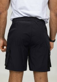 Shorts cargo noirs avec une taille élastique, des poches latérales et une texture lisse. Le design comprend une coupe décontractée et une jambe droite.