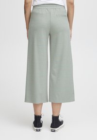 Lange broek met wijde pijpen in lichtblauw met een geruit patroon. Gemaakt van een gestructureerde stof, met een hoge tailleband en achterzakken.