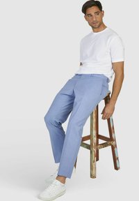 Lichtblauwe op maat gemaakte broek met een geruit patroon, voorzien van een vlakke voorkant, zijzakken en een slanke pasvorm, gecombineerd met witte sneakers.