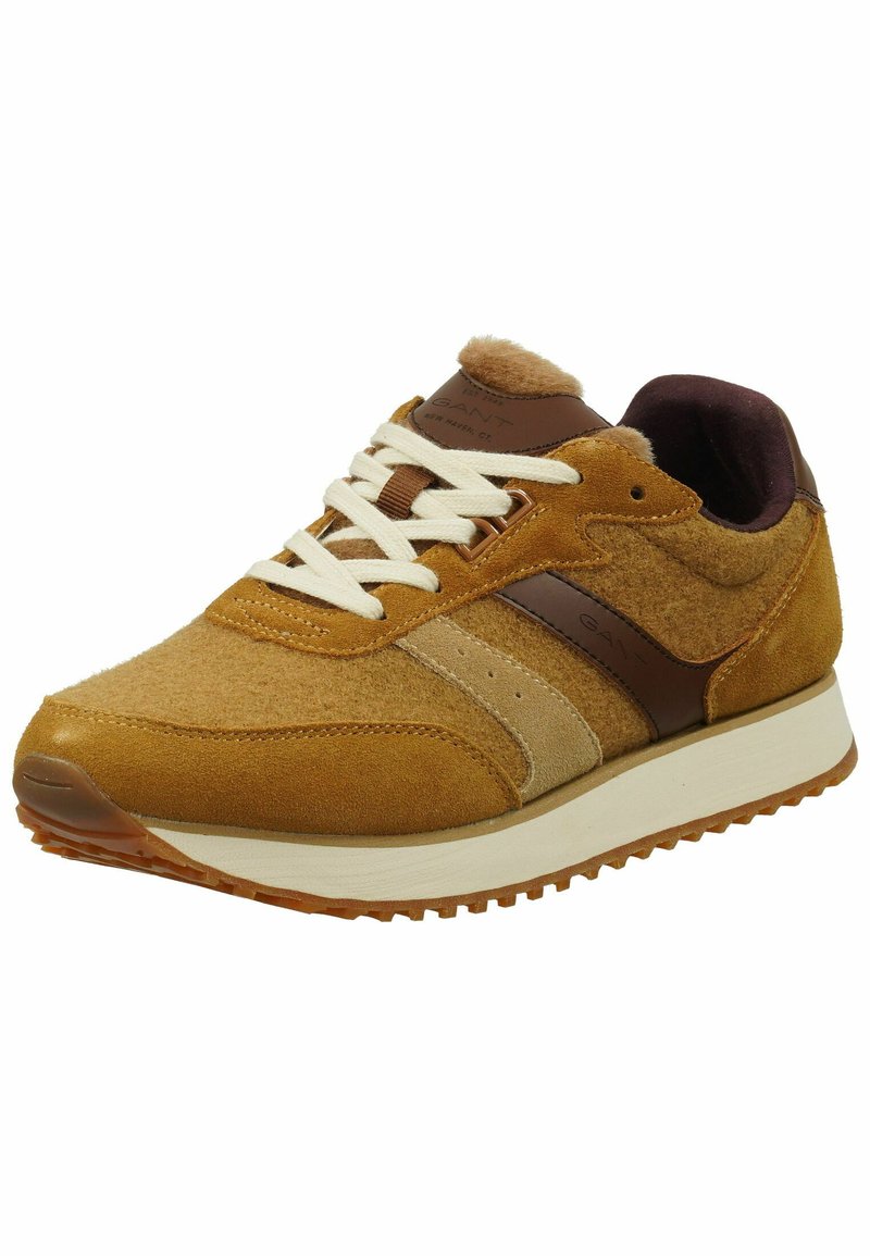 Tan suède sneaker met een gekruld bovenwerk, bruine leren accenten, crèmekleurige veters en een rubberen zool met een patroon.