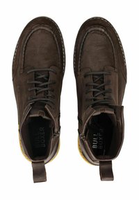 Hnědé kožené kotníkové boty s texturovaným povrchem, kulatou špičkou, šněrováním a zipem. Akcenty na žluté gumové podrážce.