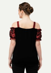 Top con spalle scoperte in tessuto nero, caratterizzato da maniche a sbuffo con motivo rosso, dettaglio arricciato e spalline decorative. Vista posteriore.