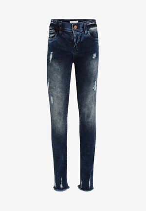 Jean skinny bleu foncé avec des patchs usés et des ourlets effilochés, avec fermeture à boutons devant et design cinq poches.