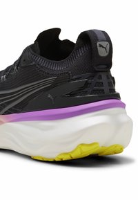 Black running shoe featuring a textured upper, purple accent on the midsole, and a chunky white outsole with yellow detailing.