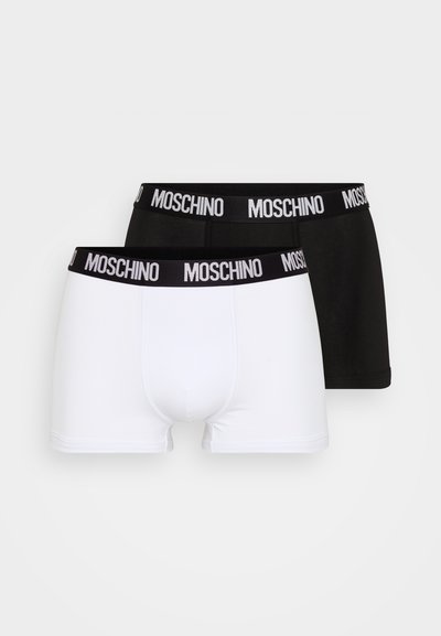 Dvoje boxeriek, jedny biele a jedny čierne, vybavené širokým elastickým pásom s logom "MOSCHINO" vytlačeným bielym písmom.