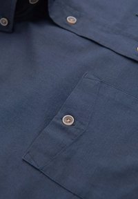Navy-Blaues Hemd mit Knöpfen und strukturiertem Stoff. Verfügt über eine aufgesetzte Brusttasche und Kunststoffknöpfe. Die Naht an Kragen und Tasche ist sichtbar.