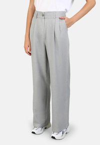 Grey high-waisted trousers with front pleats, made from lightweight fabric. Features a button closure and side pockets, paired with white sneakers.