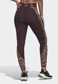 Leggings marroni con una pannello a stampa zebra in una tonalità più chiara. Realizzati in tessuto elastico, presentano un'alta vita e scarpe da ginnastica.