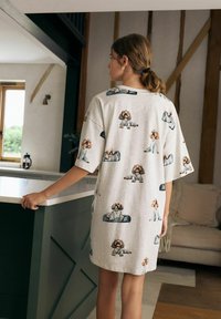 Loungewear grigio in cotone con una stampa di cani giocosa. Maniche corte e ampie e una vestibilità rilassata, che arriva a metà coscia. Design semplice e casual.
