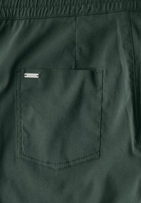 Gröna tyggshorts med en sydd bakficka och en liten metalltagg märkt "E Street One". Slät textur med en enfärgad design.