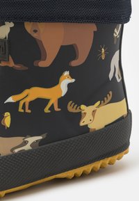 Gummistövel med en mörk bakgrund som har färgglada djurtryck, inklusive en räv, en björn och en älg, med en strukturerad svart sula.