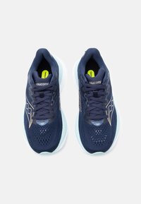 Ζευγάρι ναυτικό μπλε παπούτσια τρεξίματος Saucony με αεριζόμενο δίχτυ, ανοιχτό μπλε σόλες και μαύρα κορδόνια, από πάνω σε λευκό φόντο.