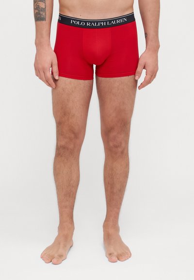 Crvene bokserice s tijesnim fitom, napravljene od mekanog materijala. Sadrže crni pojas s logom "POLO RALPH LAUREN".