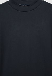 T-shirt girocollo di un blu navy scuro realizzato in morbido tessuto misto cotone. Presenta una superficie liscia e un design minimalista senza motivi visibili.