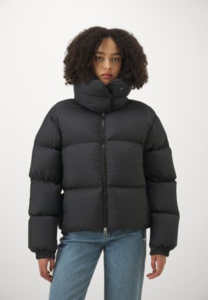Black puffer jacket with smooth, shiny fabric, high collar, and zip closure. Features elastic cuffs and a boxy shape for warmth.