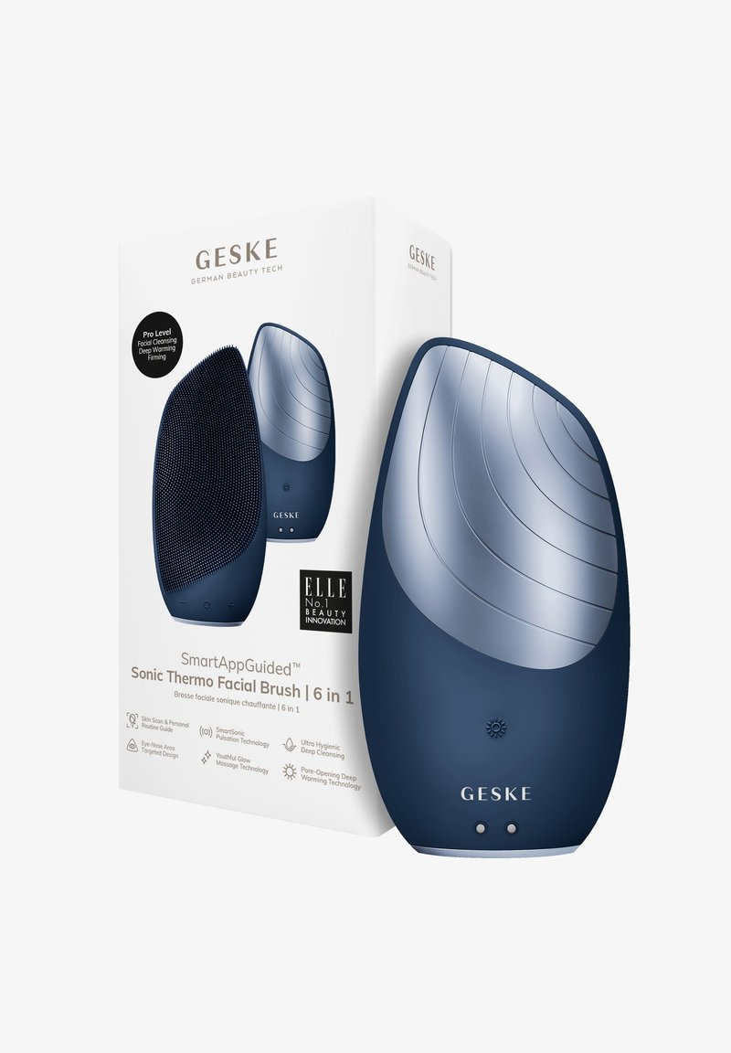 Brosse faciale sonique bleue avec une surface en silicone texturé et un sommet lisse, emballée dans une boîte blanche comportant les détails du produit et les logos.