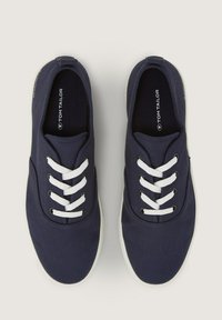 Sneakers in tela blu con lacci bianchi, punta rotonda e una superficie testurizzata. Include il logo del marchio all'interno del colletto.