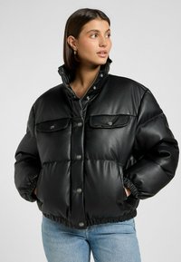 Chaqueta acolchada negra en cuero sintético con un alto cuello, botones a presión y dos bolsillos frontales. Presenta puños y dobladillo elásticos para un ajuste ceñido.