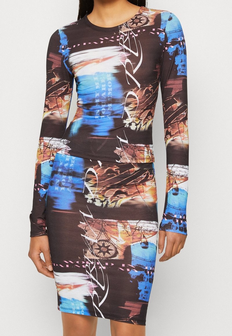 Top negro ajustado de manga larga y falda con estampados gráficos abstractos multicolores en azul, naranja y blanco, y detalles de texto en cursiva.