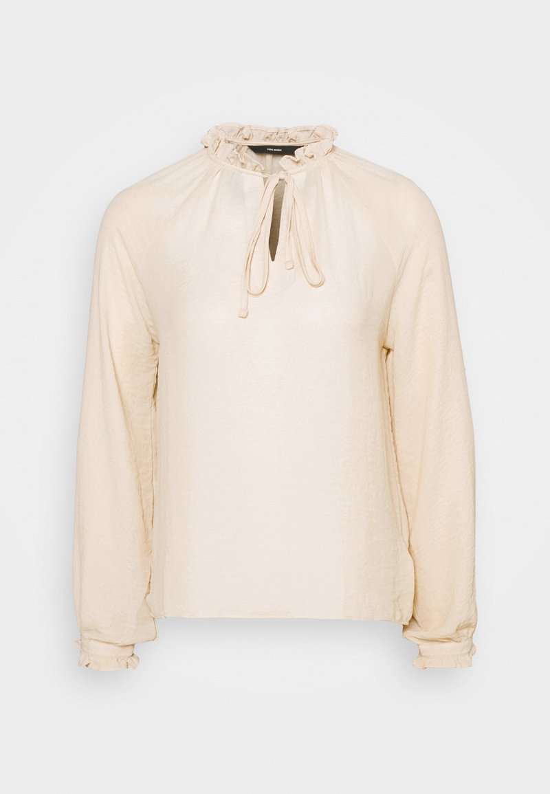 Krämfärgad långärmad blus med volangdetalj vid halsen och knytning. Har en mjuk textur och en avslappnad passform med elastiska ärmslut.