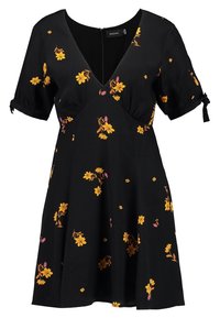 Svart klänning med korta puffärmar; har en djup V-ringning och blommönster i gult och rosa. Tyget har en mjuk textur.