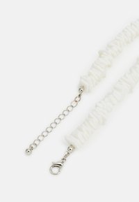 White textured necklace featuring uneven, wavy pieces, silver hardware with a lobster clasp and extender chain for adjustable length.