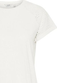 T-shirt bianco a maniche corte, con un motivo in pizzo testurizzato sulle spalle. Tessuto morbido con scollatura rotonda e vestibilità comoda.