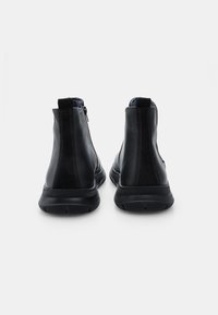 Botas de tobillo de cuero negro con un acabado suave, cierre de cremallera y suelas de goma. Presenta detalles cosidos en los laterales y un tacón texturizado.