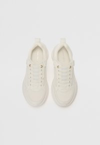 Baskets en mesh blanches avec un bout arrondi, une partie supérieure en textile et des lacets élastiques. Présente un logo discret sur la semelle intérieure et une semelle rembourrée.
