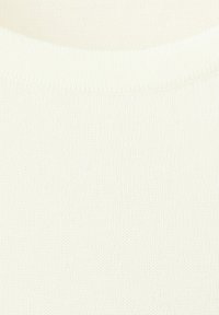 Close-up of a cream-colored, finely knitted sweater showing the ribbed crew neckline and smooth texture.