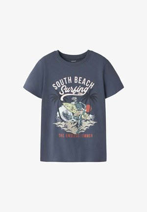 T-shirt bleu marine avec un squelette surfant sur une vague, des palmiers en arrière-plan, et le texte "South Beach Surfing Club" et "The Endless Summer."