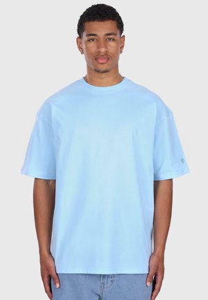 Light blue cotton t-shirt with a relaxed fit, crew neck, and short sleeves. Features minimalistic design and subtle branding on the sleeve.