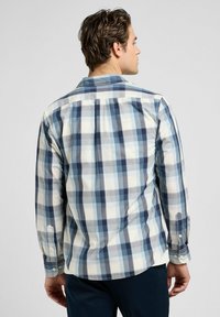 Camicia a quadri da uomo in tonalità di blu e crema, con colletto button-down, maniche lunghe e uno spacco sulla spalla posteriore per maggiore comfort.