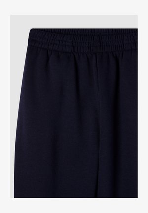 Pantaloni sportivi blu navy con vita elastica e texture morbida e liscia; presentano un delicato dettaglio di cucitura lungo la vita.