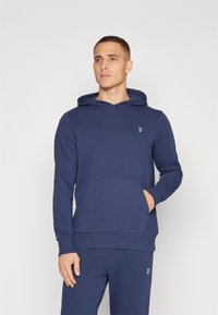 Felpa con cappuccio blu navy realizzata in tessuto morbido, dotata di tasca a marsupio e di un piccolo logo sul petto; design aderente con polsini a coste.