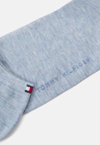 Svijetloplave pamučne čarape s rebrastim rubom, s malom oznakom u crvenoj, bijeloj i plavoj boji i tekstom "TOMMY HILFIGER" u plavoj boji.