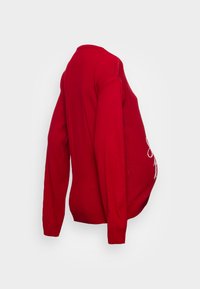 Red knit maternity sweater with long sleeves and round neckline. Features a cinched bottom and decorative white stitching on the front.