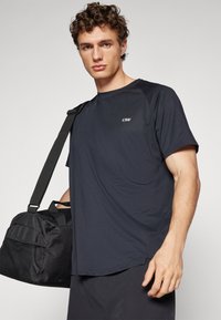 Camiseta deportiva de color azul oscuro en una tela ligera y texturizada. Presenta un cuello redondo, mangas cortas y un pequeño logo en el pecho.