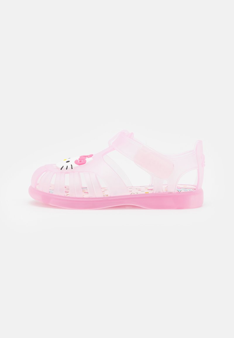Pink transparent sandals with cut-out design and adjustable strap. Features a Hello Kitty motif on the toe. Textured insole with colorful patterns.