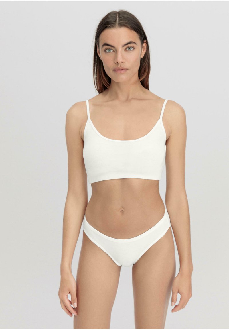 Bralette bianca in cotone con spalline sottili e scollatura a giro, abbinata a un perizoma a vita bassa coordinato, con una texture liscia e un design minimale.