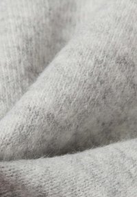 Jasnoszara dzianina o miękkiej, puszystej teksturze. Posiada subtelny melanżowy wzór i przytulny, ciepły wygląd.
