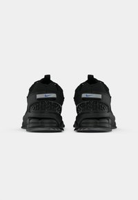 Čierne športové topánky Nike s sieťovinovým zvrškom, textúrovanými akcentmi a robustnou podrážkou, s modrým logom na päte.